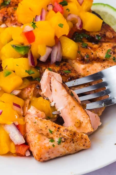 A bite of salmon with some salsa made with mango.