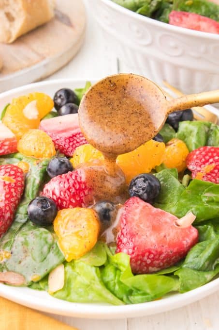 Spooning the dressing over a Strawberry Spinach Salad.
