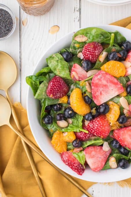 A spinach salad tossed with poppy seed dressing.